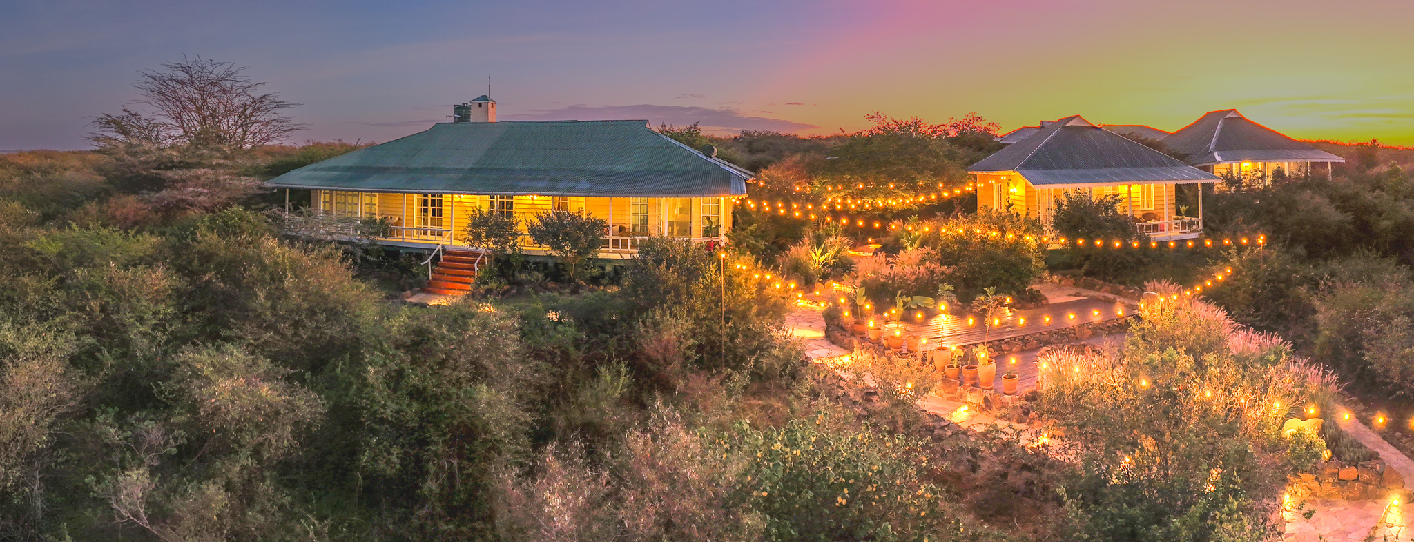 Mlima's camp buildings glowing under festoon lights at dusk in the Maasai Mara